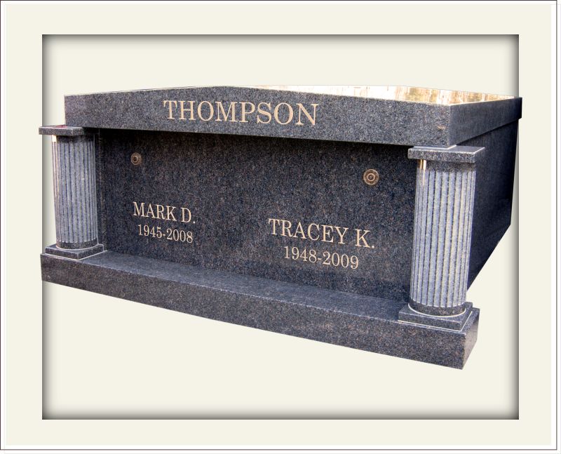 Dark grey mausoleum with two pillars and engraved family name