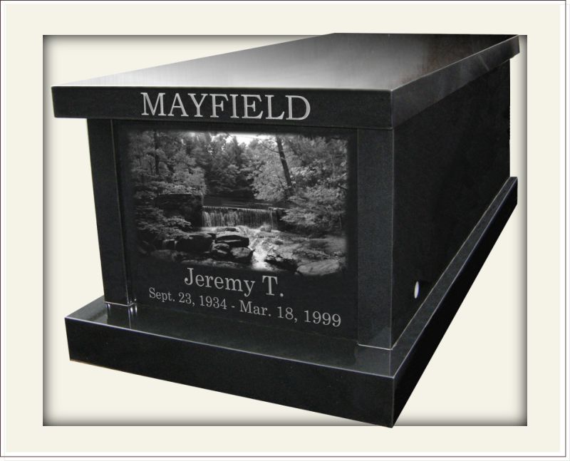 Black marble mausoleum with etched photograph of a mountain stream